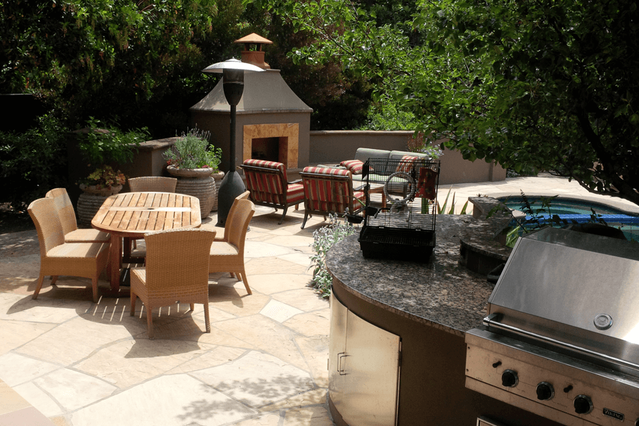 backyard outdoor kitchen with fireplace and dining area
