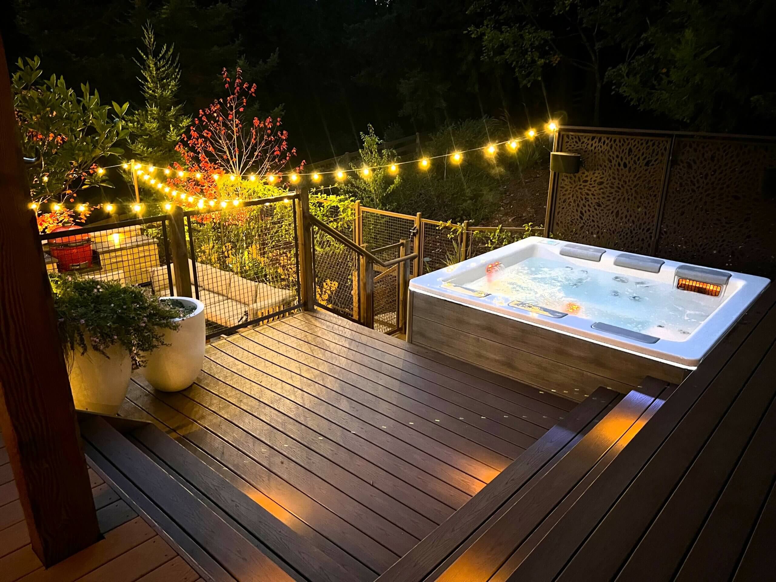Hot tub deck perched above firepit and seating area of sloped Santa Cruz backyard with a view