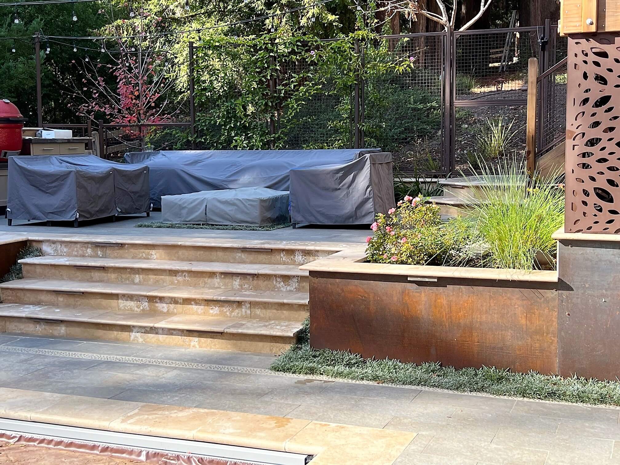 Firepit area on custom raised paver patio on sloped California backyard