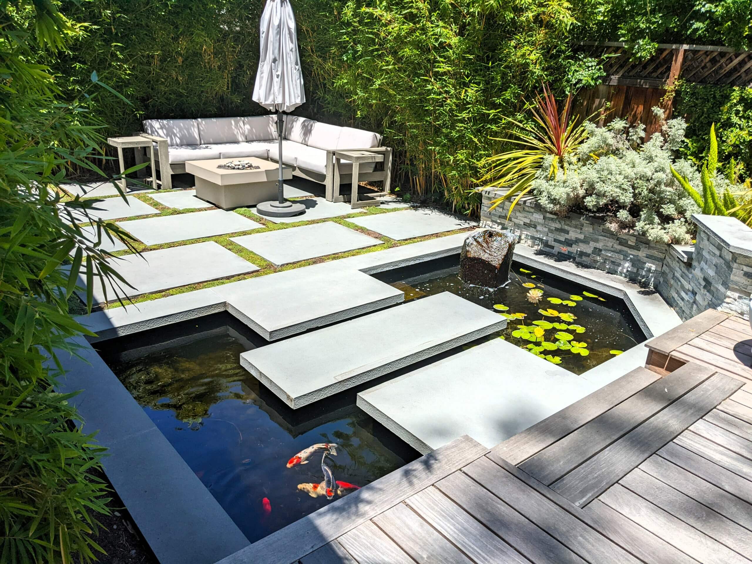 Floating stone steps crossing koi pond to backyard fire pit area
