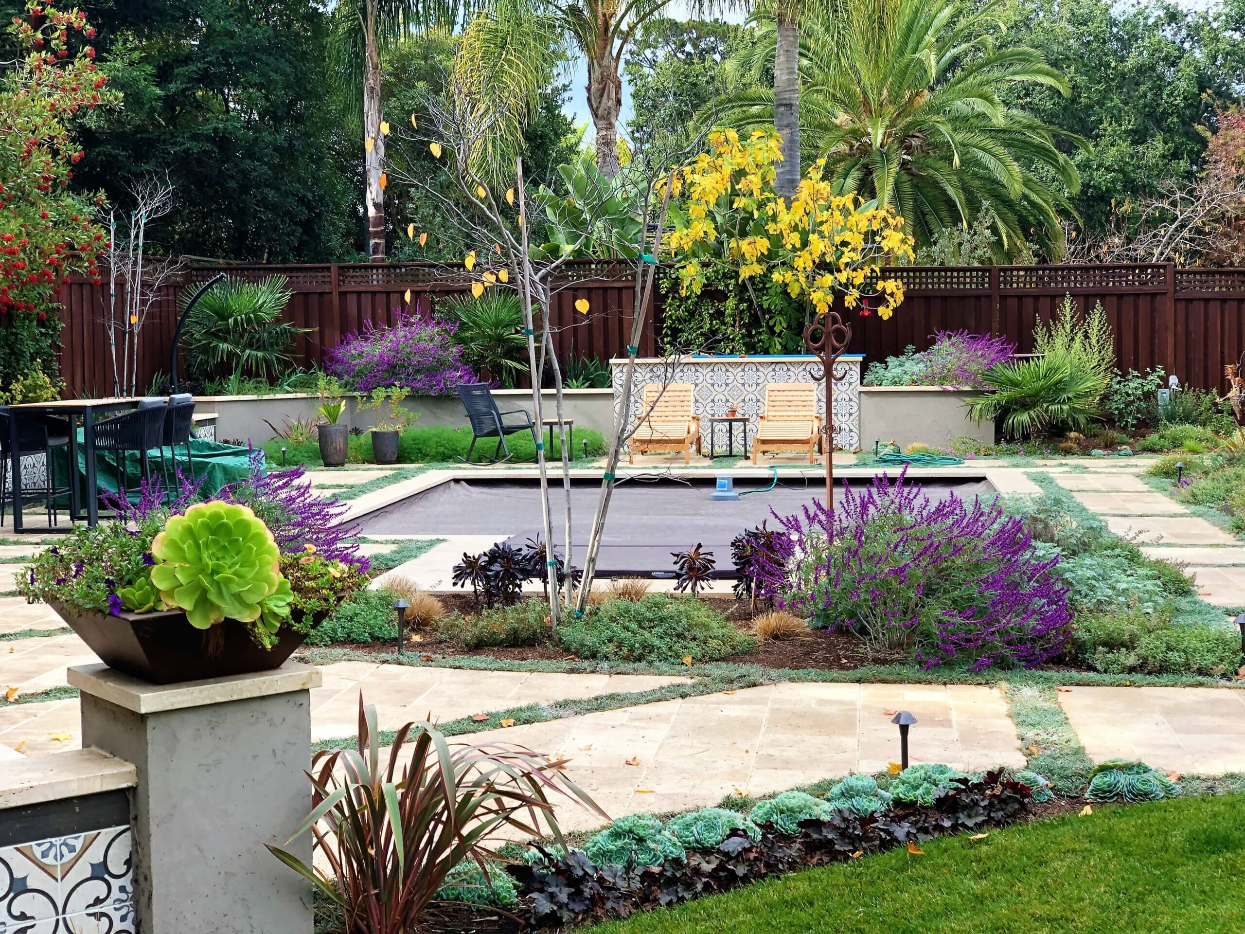 Mediterranean inspired backyard with swimming pool surrounded by lush colorful plantings