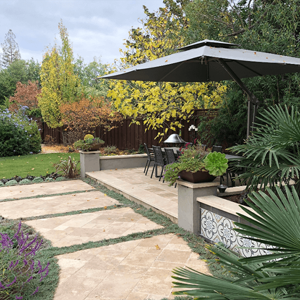 Raised patio dining area with large umbrella and beautiful California landscaping