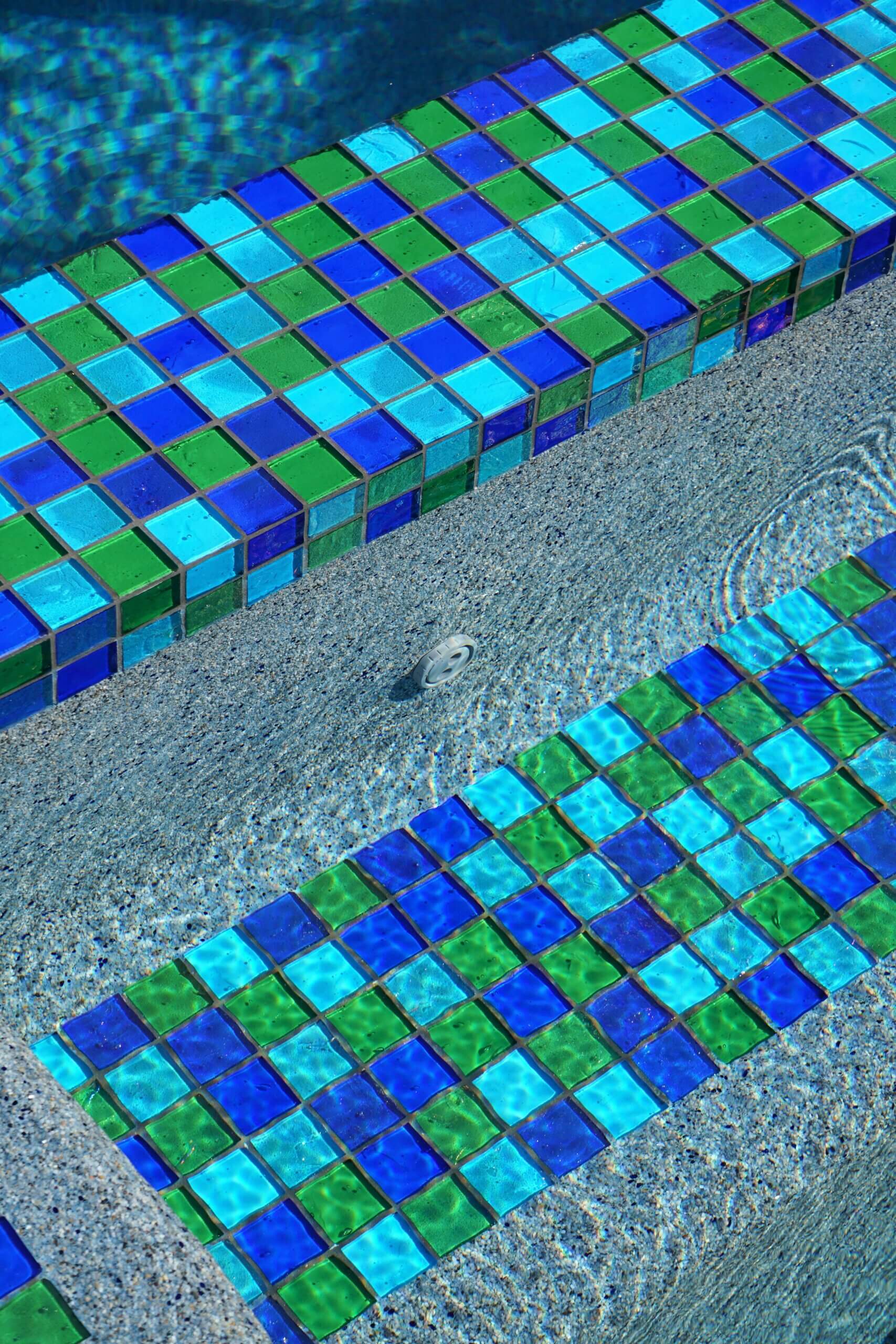 Glass tile in shades of blues and greens accenting a swimming pool