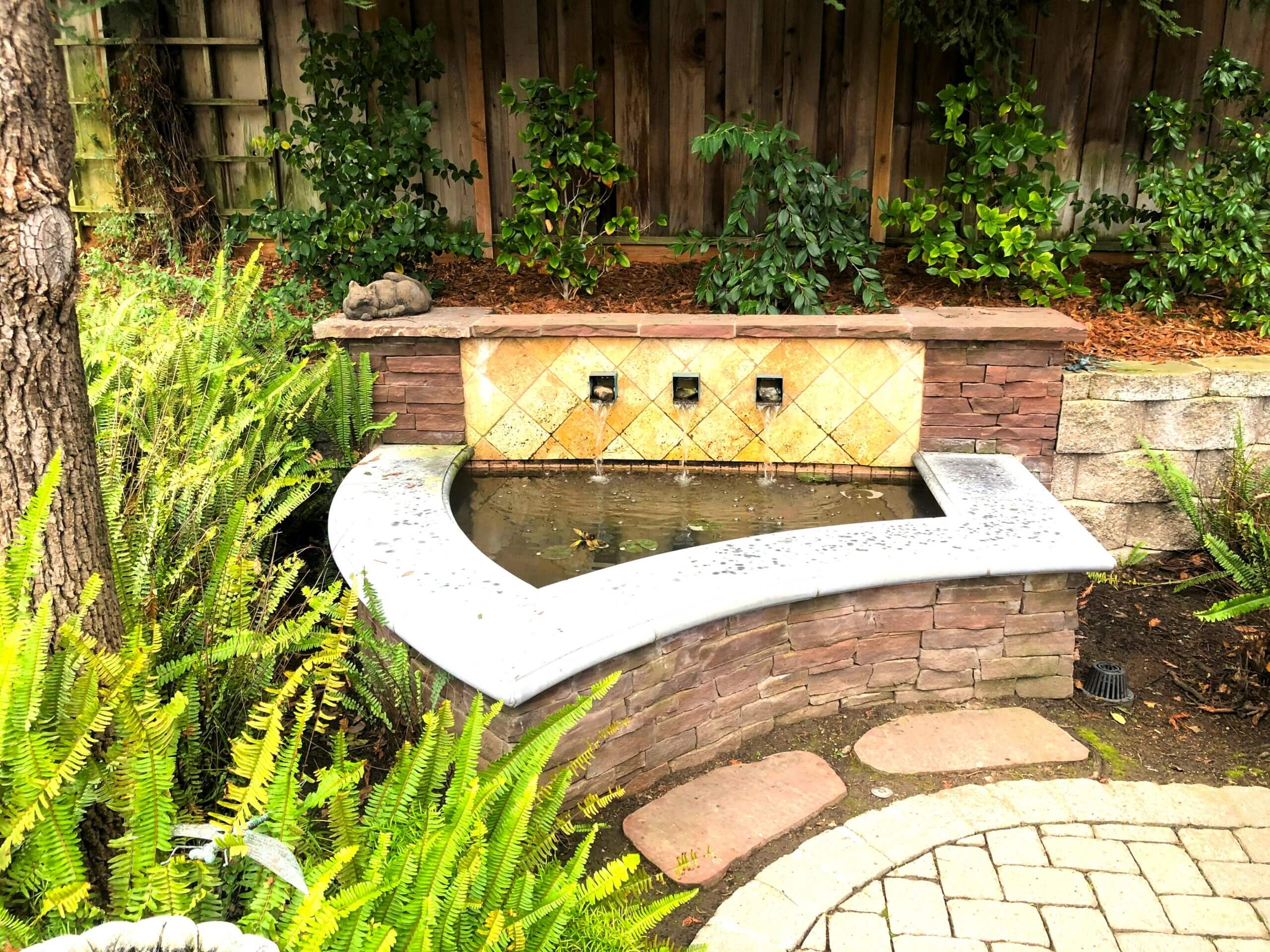 Stone water feature in backyard with three fountains