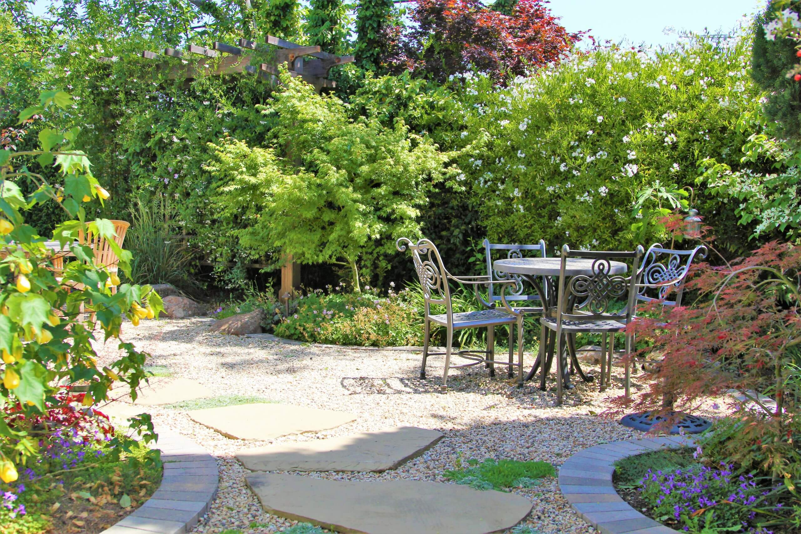 Lush natural California backyard landscape with seating areas on pea gravel and pavers amongst native plant species