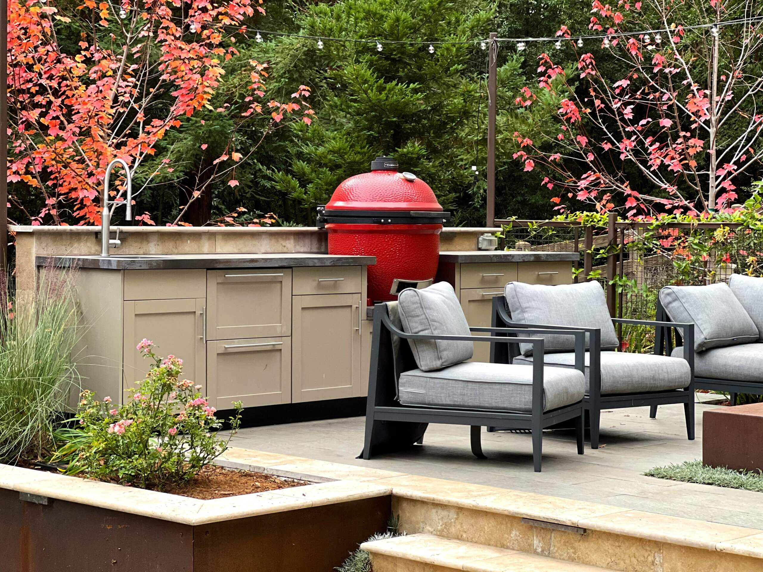 Outdoor Kitchen next to seating area and fire pit with red Kamado Joe Grill