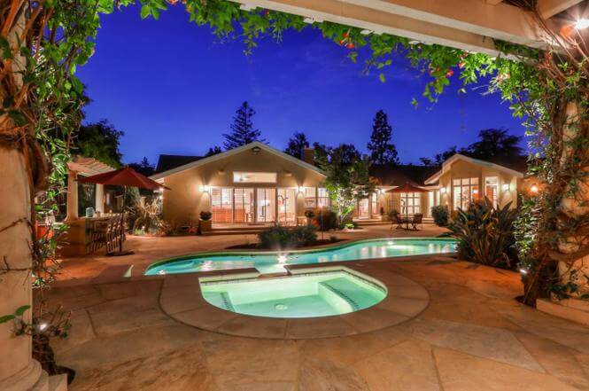 Backyard landscape with swimming pool, hot tub and arbor at night
