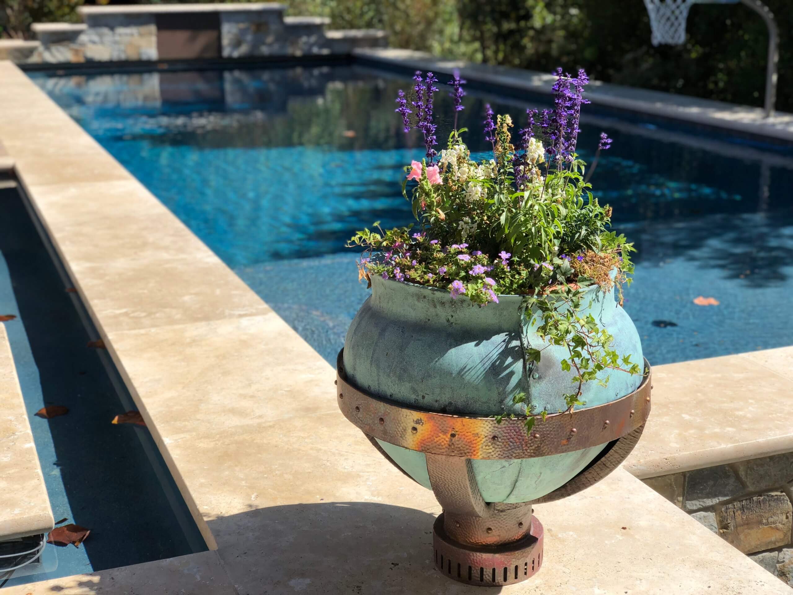 Swiming pool with clean lines flanked by custom fabricated copper orb planter.
