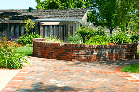 Red brick backyard patio with matching brick two foot high curved wall