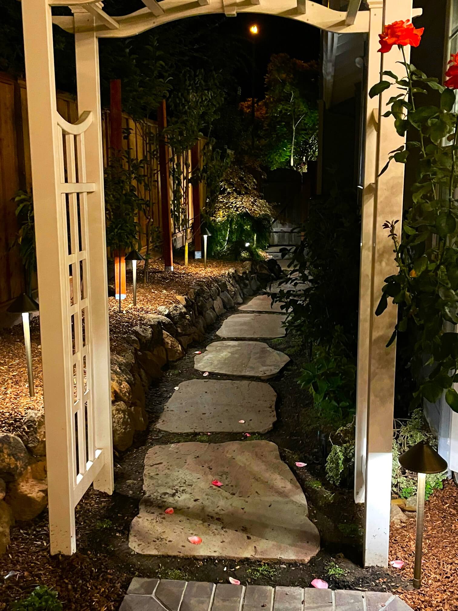Rugged large stone paver pathway down side yard at night