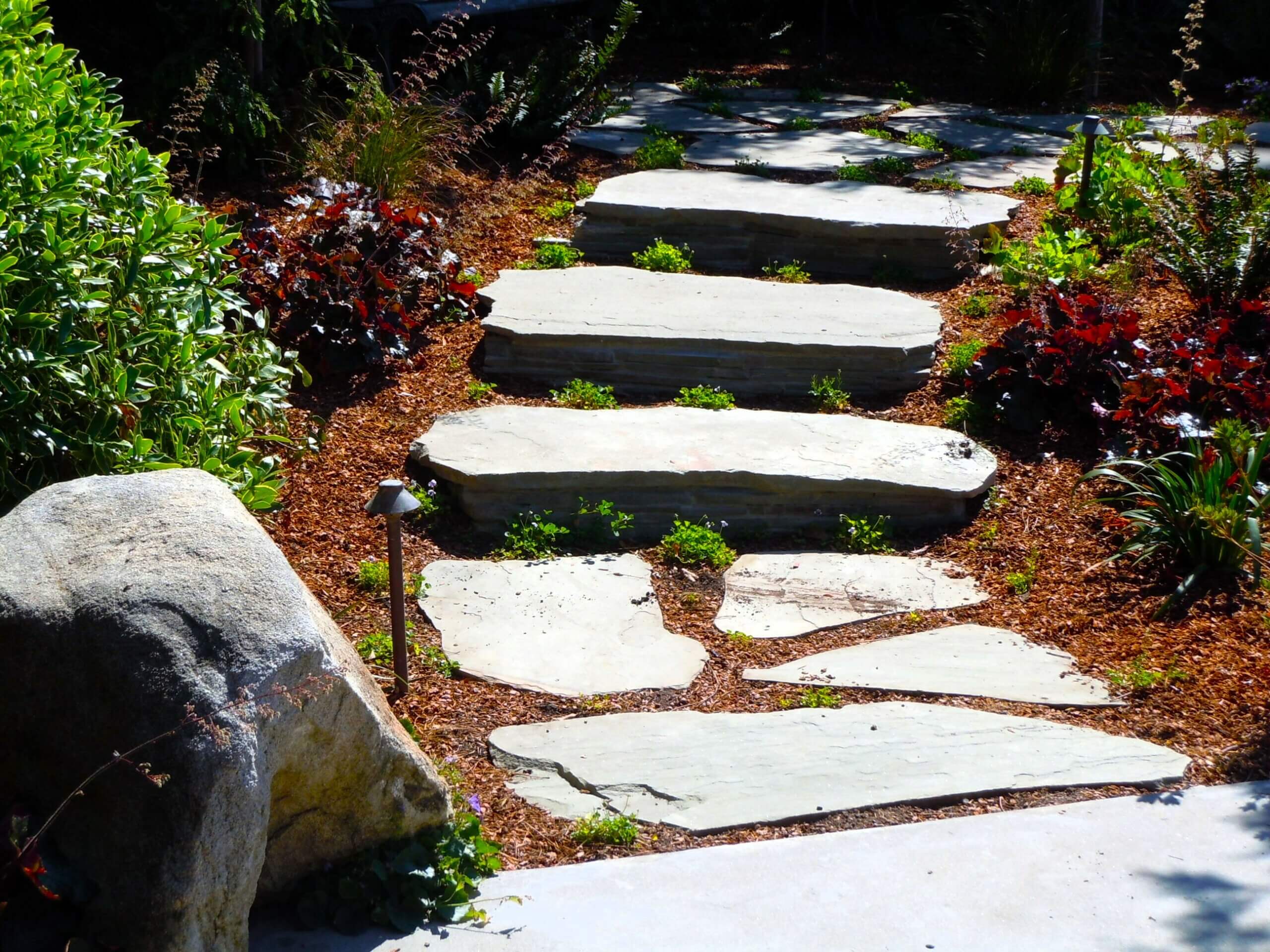 Natura stone pavers used as steps leading into shaded backyard area