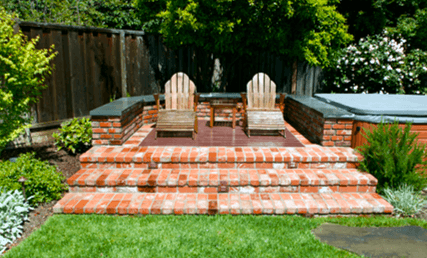 Raised brick seating patio in the shade of backyard trees
