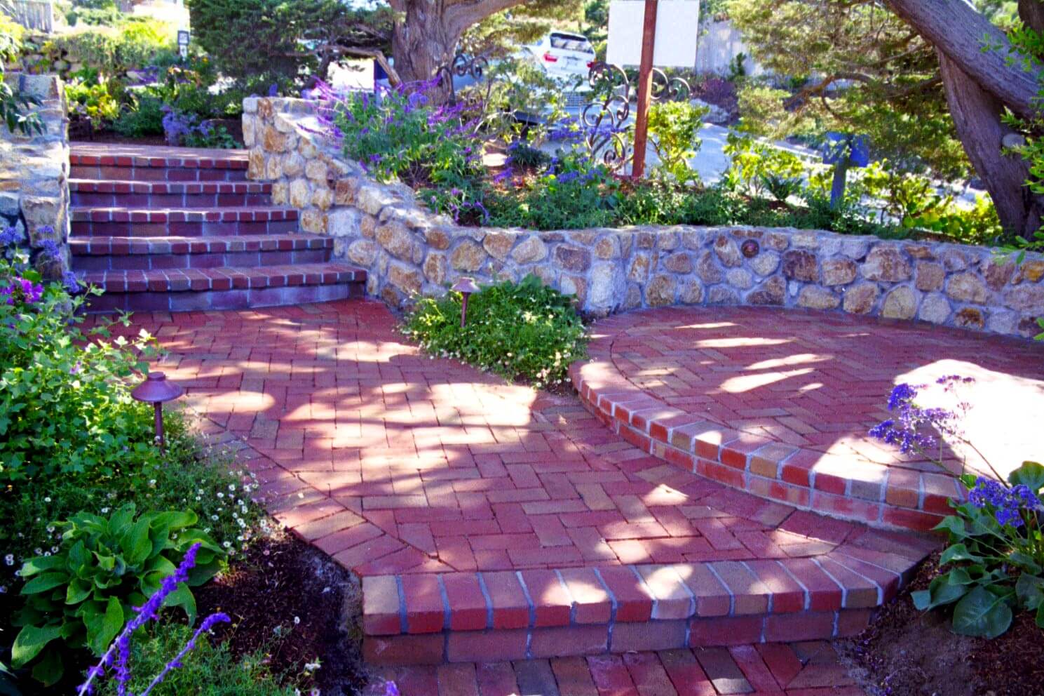 Custom brick stairs with stacked stone wall surround and round terraced seating area