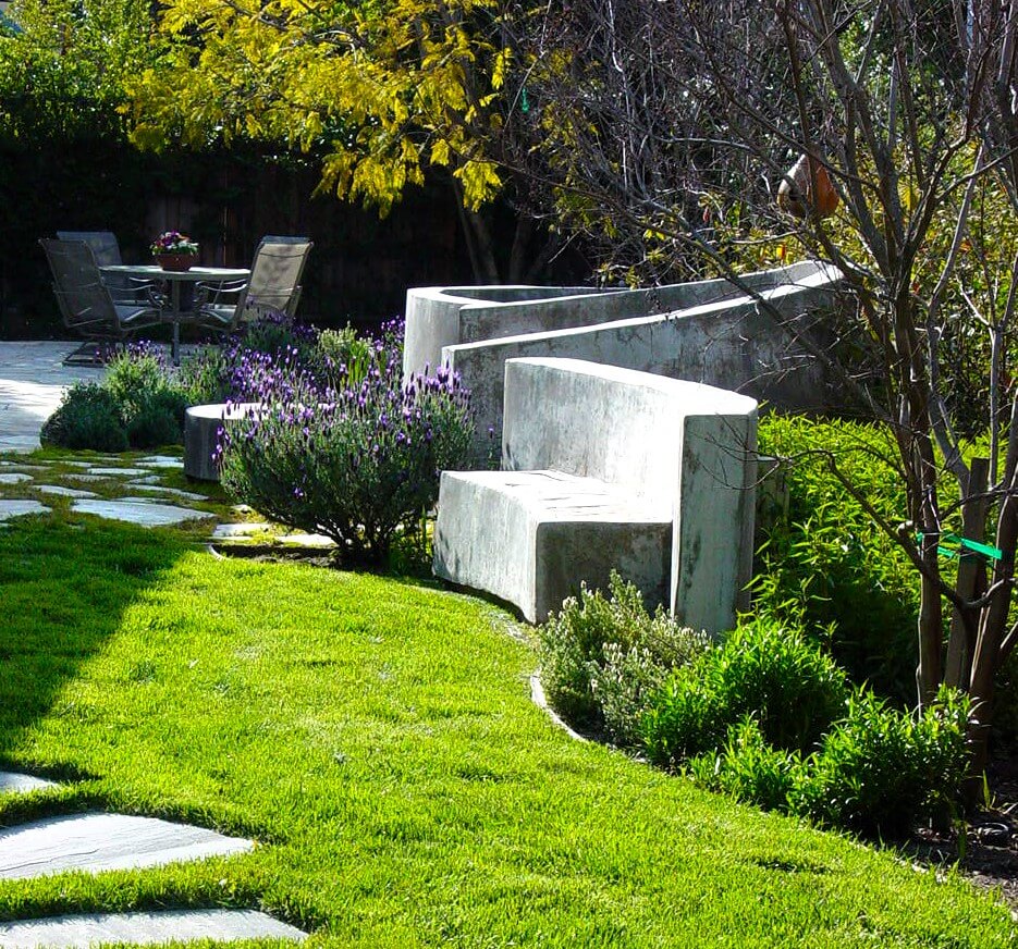 Sculptural curved custom concrete seating wall in natural backyard setting