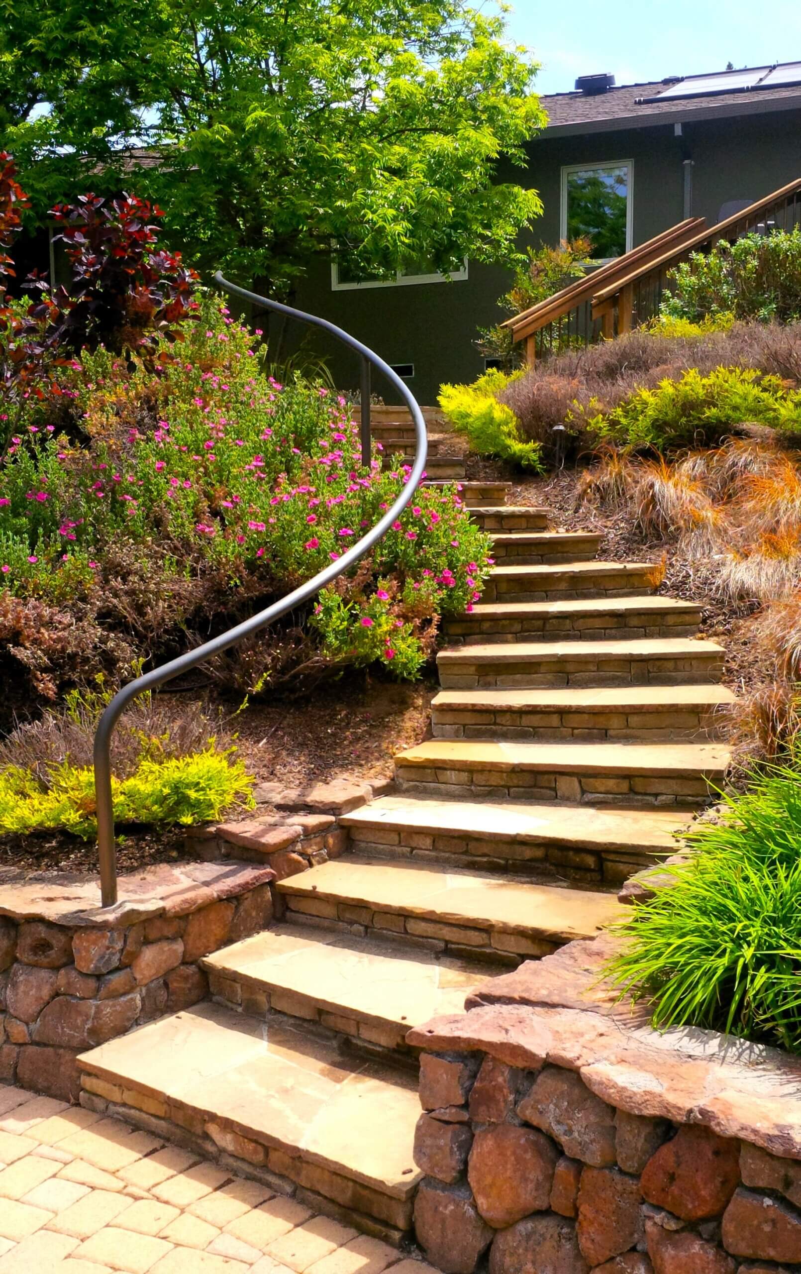 Lovely stone stairs leading from walkway to front door of California home with local plantings for a natural, organic look