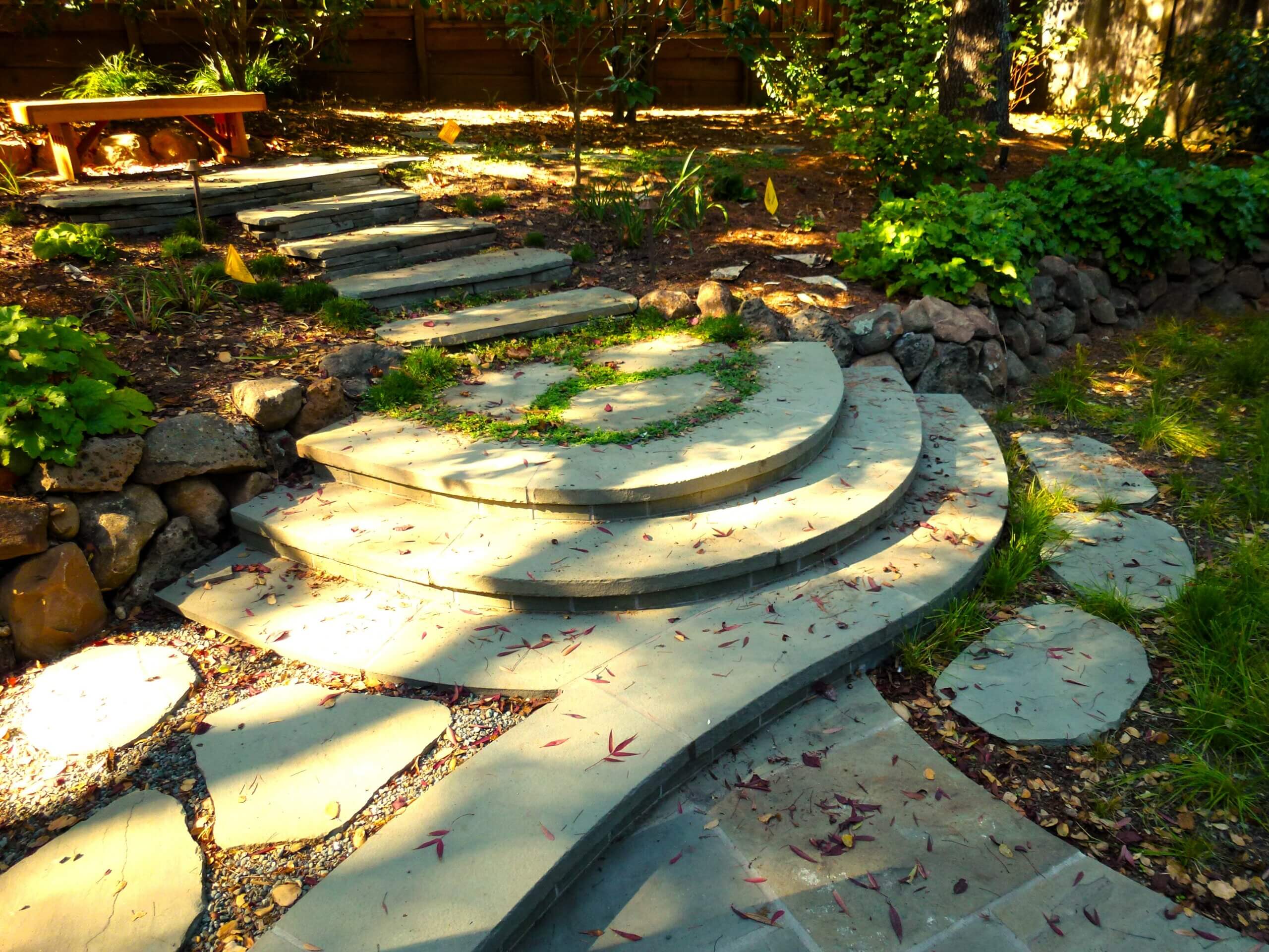 Custom stone steps mixing irregular shaped stone with sleek modern stone leading to backyard seating area