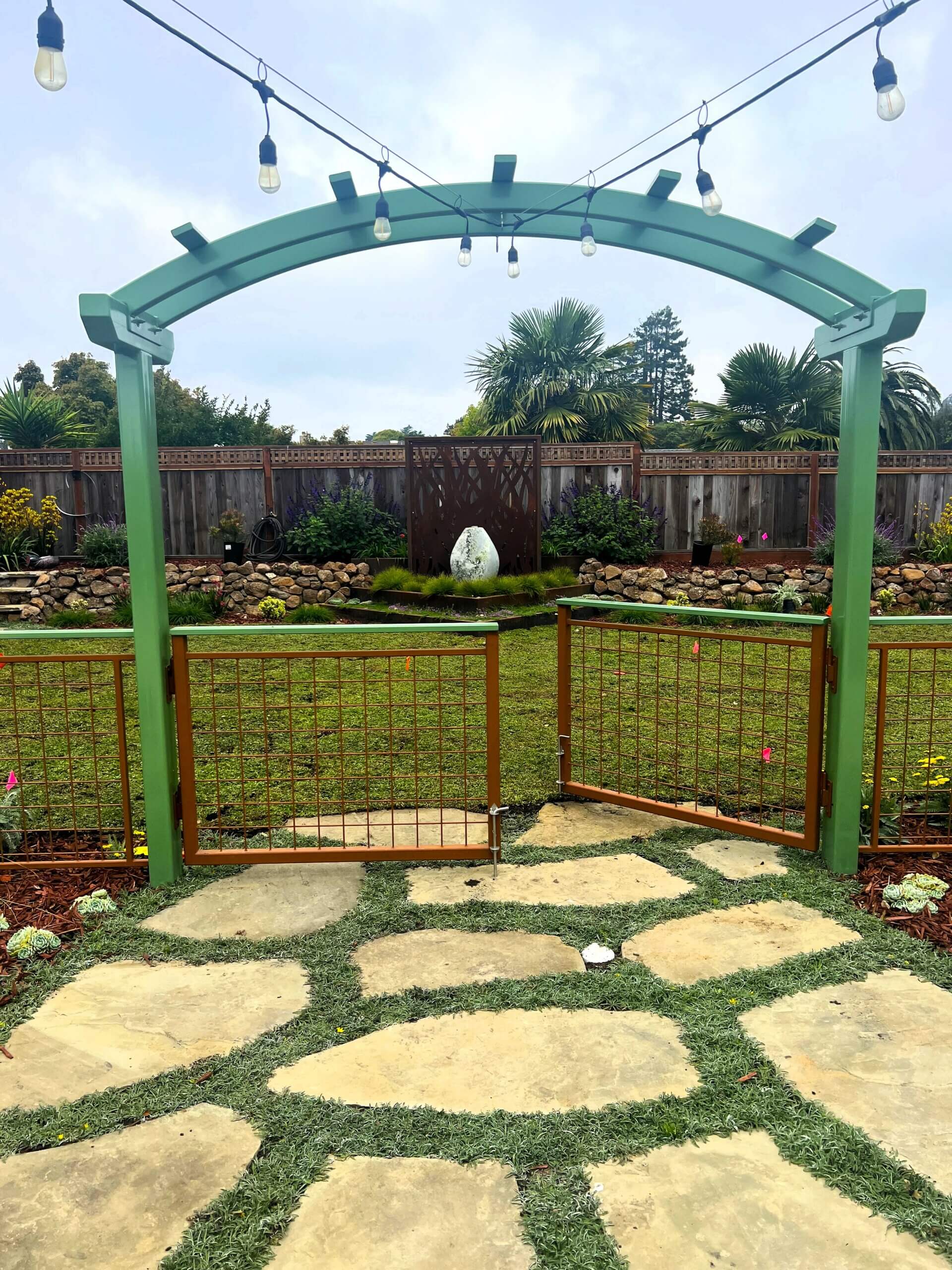 Green arbor with powder coat metal fence painted in green accents