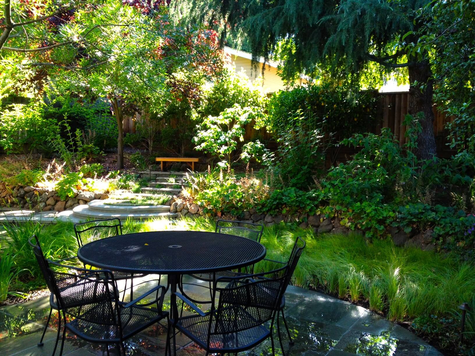 Shaded backyard patio with hidden seating area in background