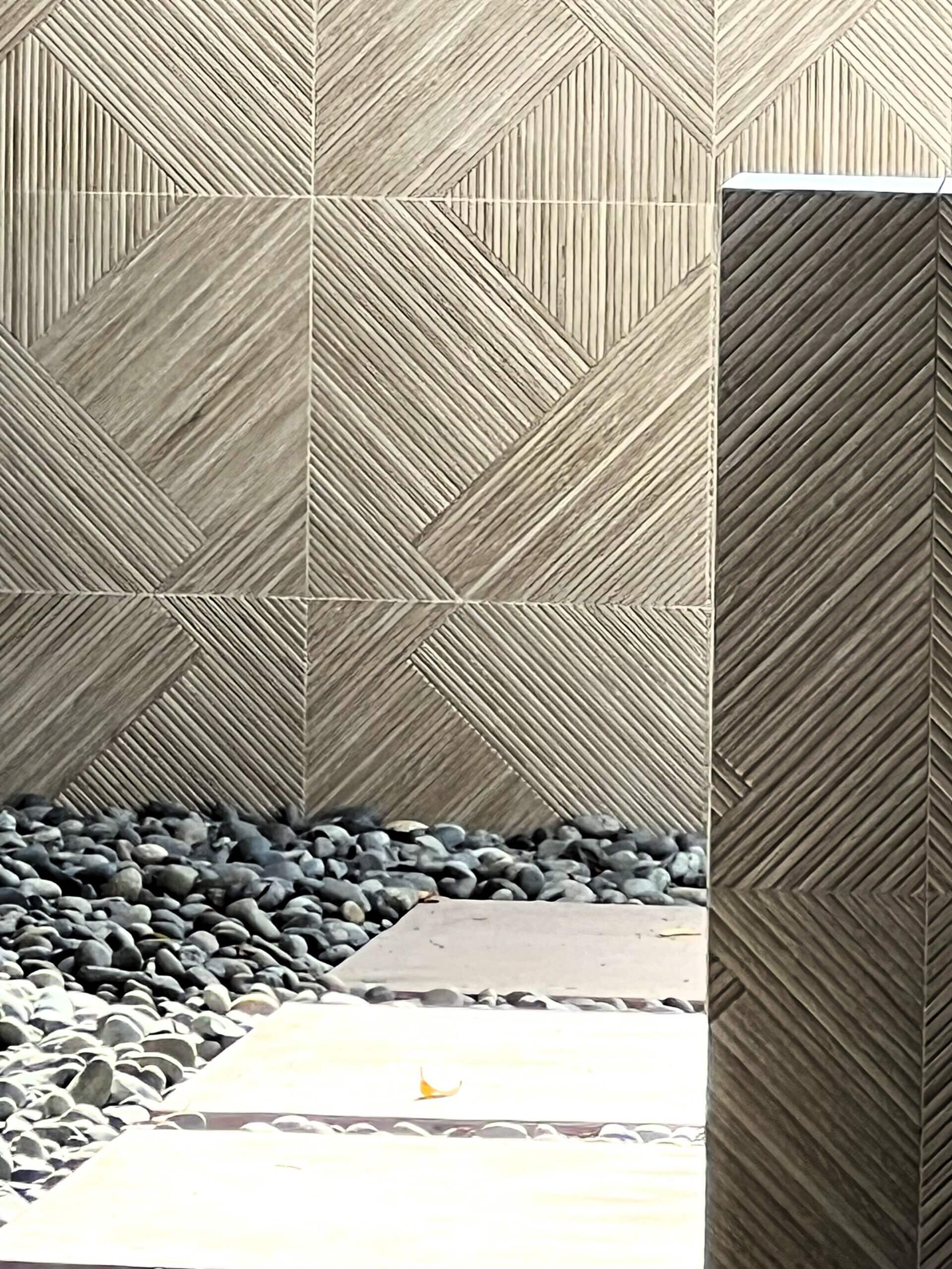 Close up of concrete wall covered in geometric grey tile for Eichler home landscape remodel
