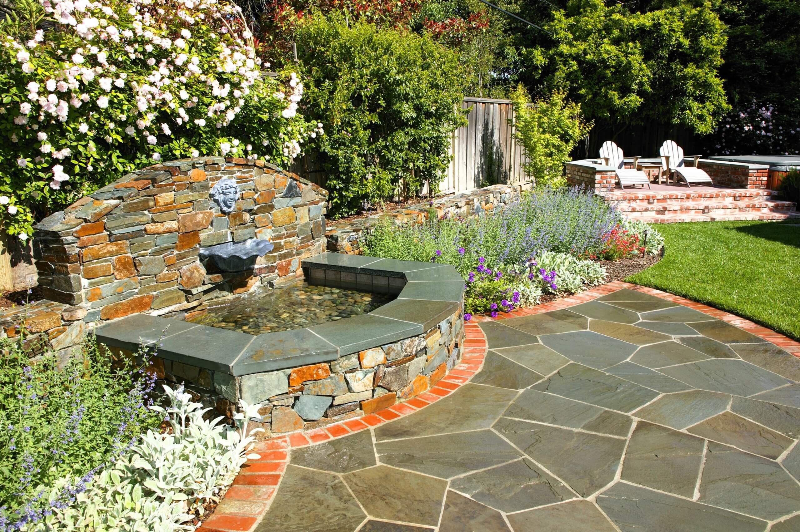 Custom stone ad brick backyard fountain with running water into pebble-filled pool
